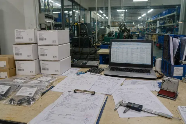 Verification desk with reports, barcode labels, cartons, and buyer review documents.